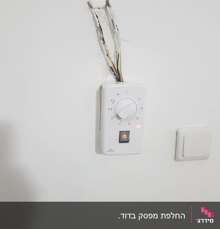 חוטי חשמל חשופים ליד תרמוסטט על קיר לבן